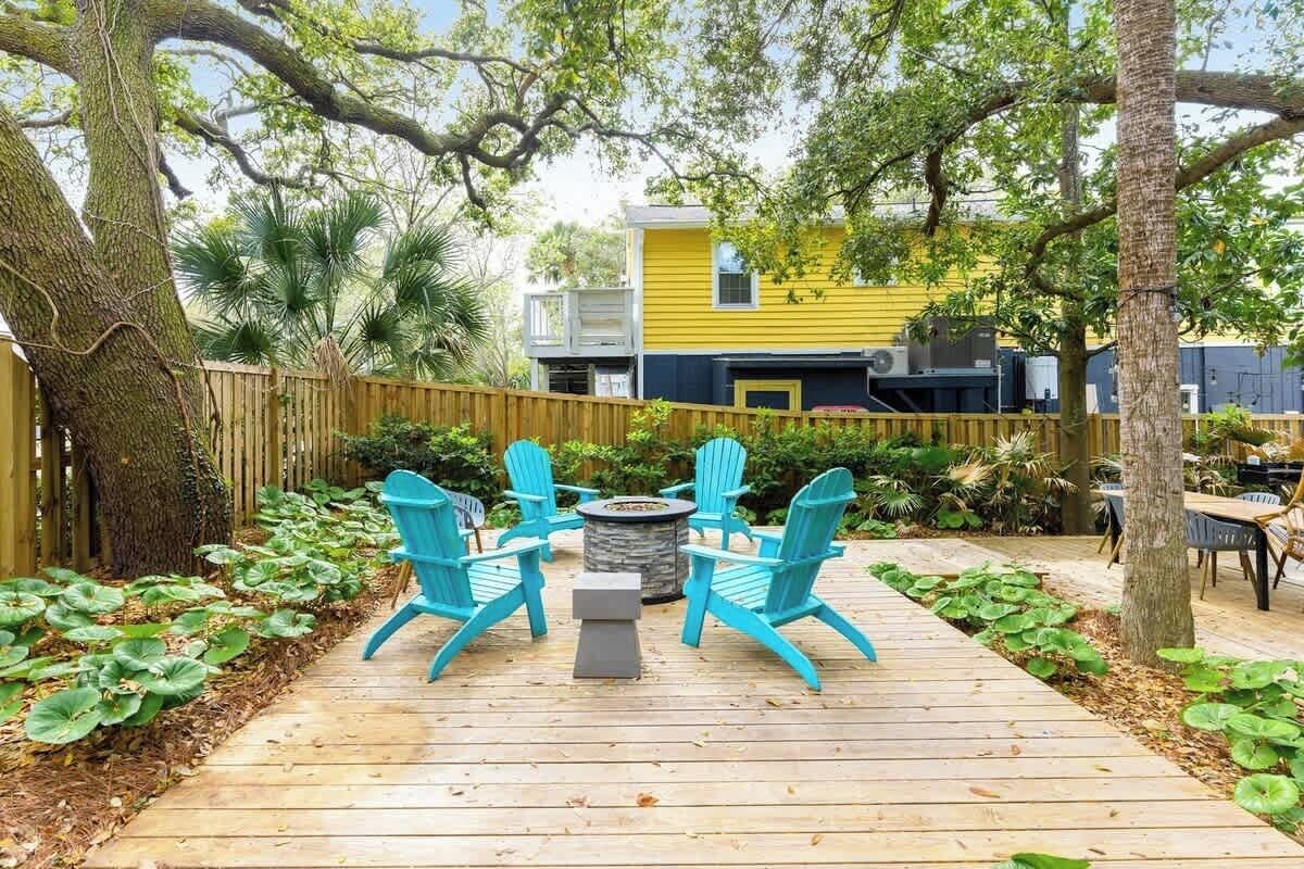 Una terraza de madera con un hogar y cuatro sillas Adirondack azules.
