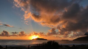 Ein Sonnenuntergang über dem Meer mit Wolken und einer entfernten Insel.