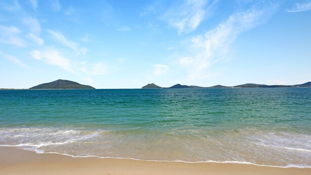 A beach with clear turquoise water, gentle waves, and distant islands under a clear sky. - Moola Palms - Pet Friendly (Hawks Nest)