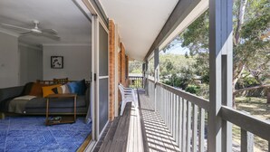A balcony with a view of the surrounding area, a sofa with cushions, and a ceiling fan. - Moola Palms - Pet Friendly (Hawks Nest)