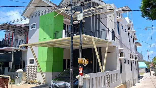 Un immeuble résidentiel à plusieurs étages, doté d’une façade verdoyante, d’un balcon et d’une voiture garée.
