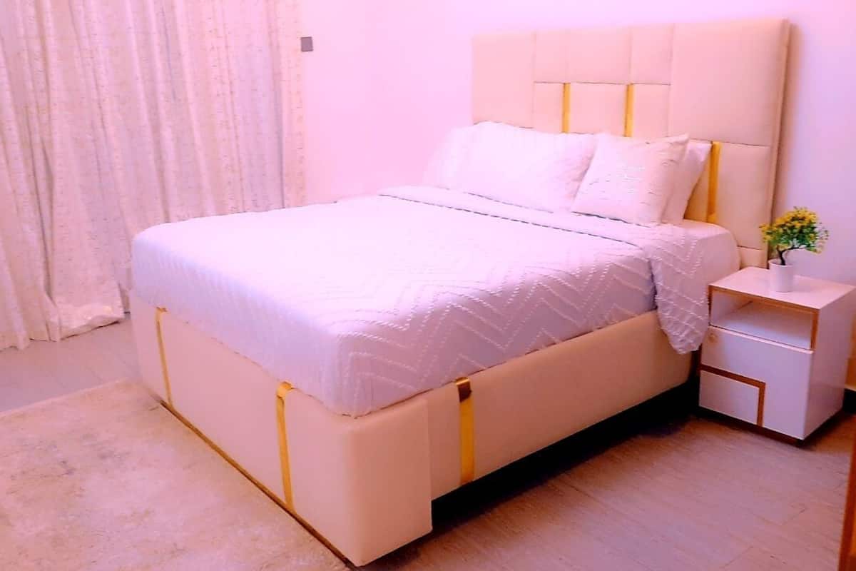 Un dormitorio ordenado con cama, mesita de noche y una planta pequeña.