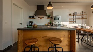 A modern kitchen with a central island, bar stools, a microwave, and a dining area with a table and chairs.