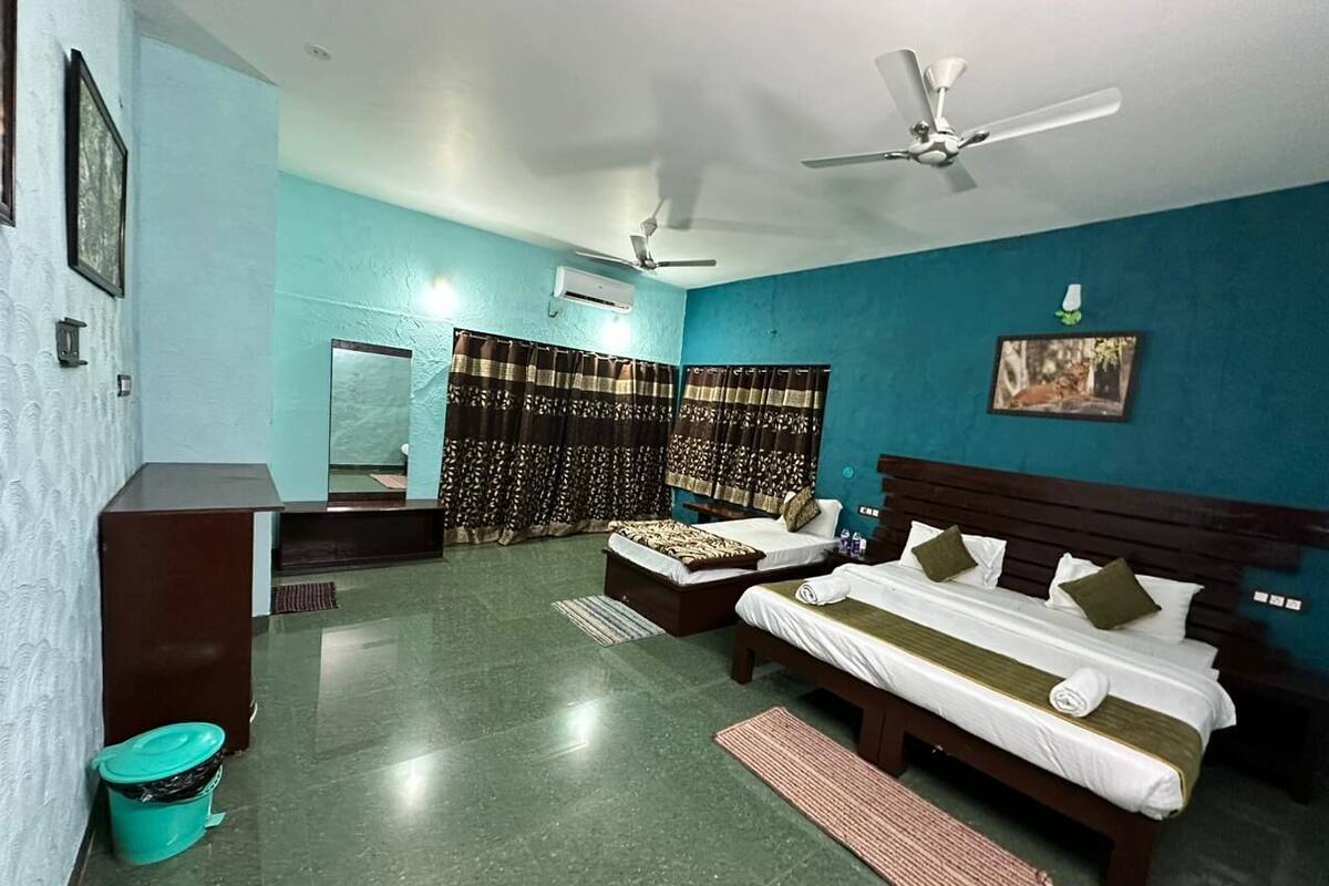 A hotel room with two beds, a desk, a chair, a ceiling fan, and a window with curtains.