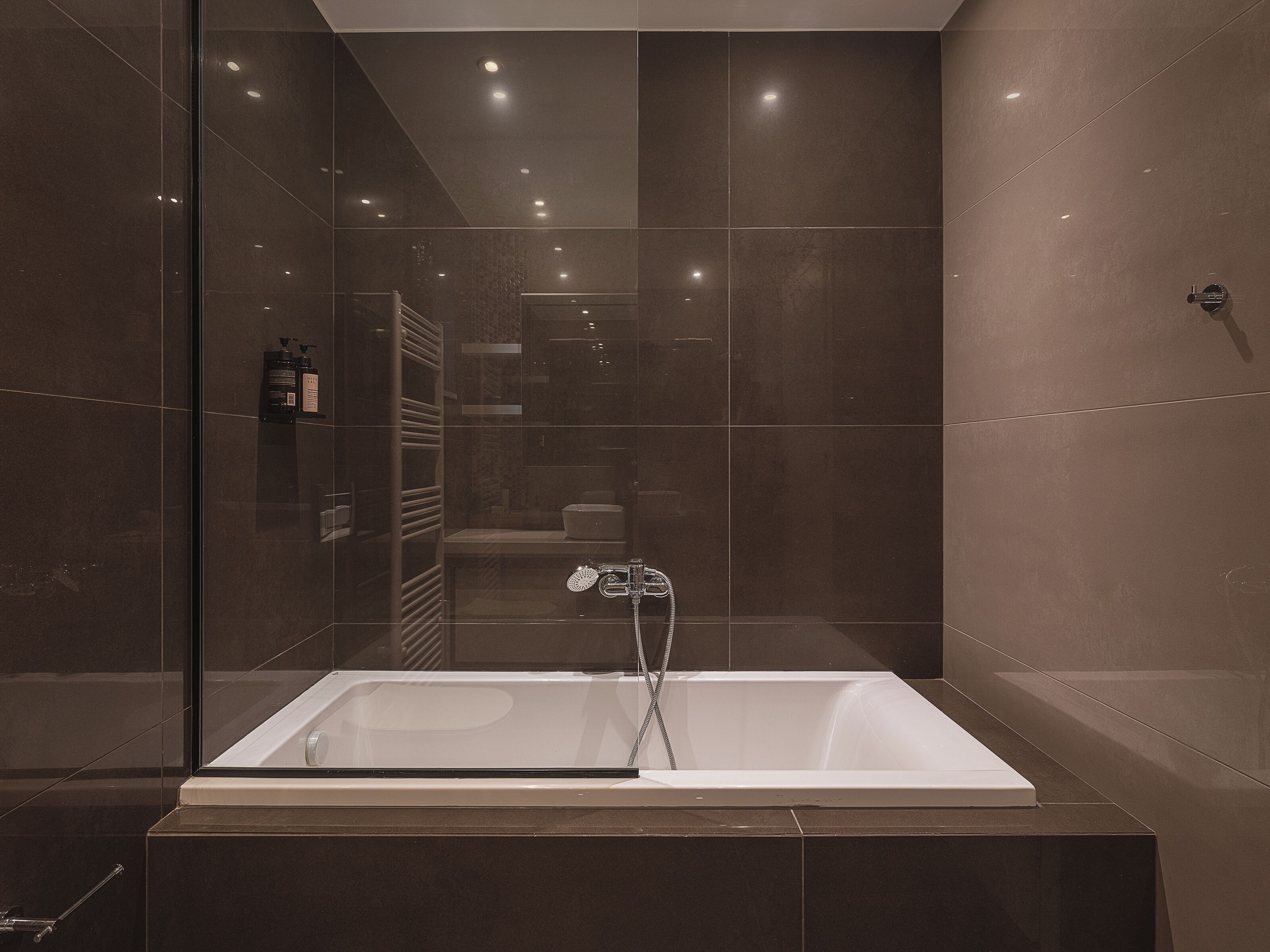 A modern bathroom with a large bathtub, a glass shower enclosure, and a visible towel rack.