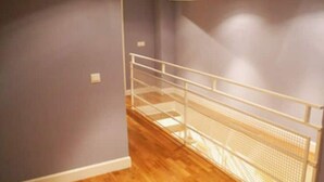 A hallway with wooden flooring and a white metal railing. - Casa en Pleno Centro (Sevilla)
