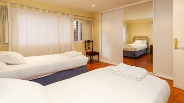A hotel room with two single beds, a chair, and a sliding door leading to another room. - Casa en Pleno Centro (Sevilla)