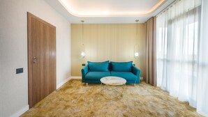 A modern living room with a teal sofa, a round coffee table, and a patterned carpet. - Yasu Luxury Rooms (Bucharest)