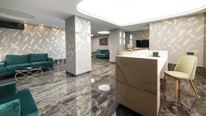 A modern hotel lobby with a reception desk, green sofas, and a marble floor. - Yasu Luxury Rooms (Bucharest)