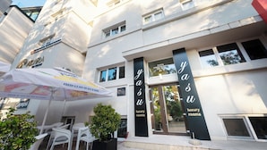 A hotel with a modern facade, luxury rooms, and outdoor seating area with umbrellas. - Yasu Luxury Rooms (Bucharest)