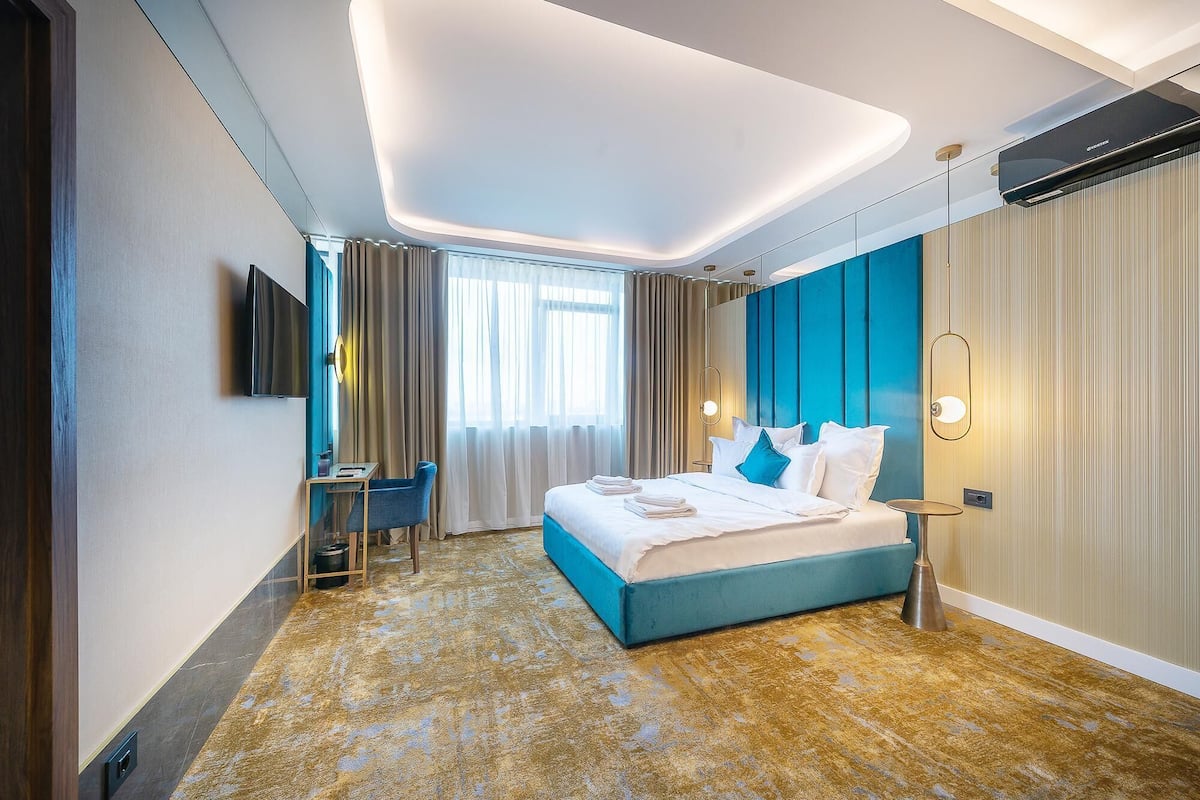 A modern hotel room with a large bed, a desk, and a TV.