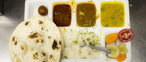 A meal with rice, flatbread, and various sauces on a white plate.