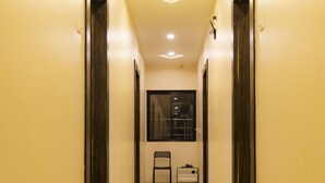 Un pasillo con alfombra verde que conduce a una habitación con ventana y una silla.