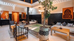 A spacious indoor area with a central seating area, a large decorative plant, and a pool. - Riad Rodaina & Spa (Marrakech)