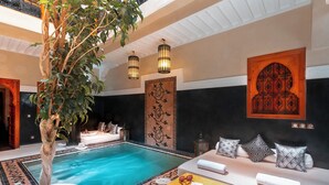 A poolside area with a lounge chair, a table with a name tag, and a decorative wall panel. - Riad Rodaina & Spa (Marrakech)