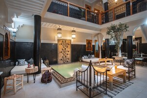 Amplia sala de estar con piscina, zonas de estar y un balcón con vistas.