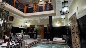 A multi-level indoor swimming pool with a glass ceiling, a lounge area with seating, and a decorative fountain. - Riad Rodaina & Spa (Marrakech)