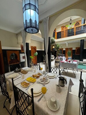 A dining area with a table set for breakfast, including plates, glasses, and a coffee pot. - Riad Rodaina & Spa (Marrakech)
