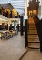 Una imponente escalera con barandillas decorativas que lleva a un balcón en el segundo piso.