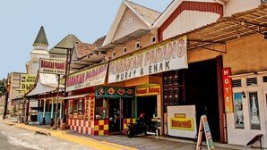 Vista de la calle con una fila de edificios, incluyendo un restaurante llamado "Masakan Padang Murah & Enak" y un hotel con un letrero que dice "HOTEL".