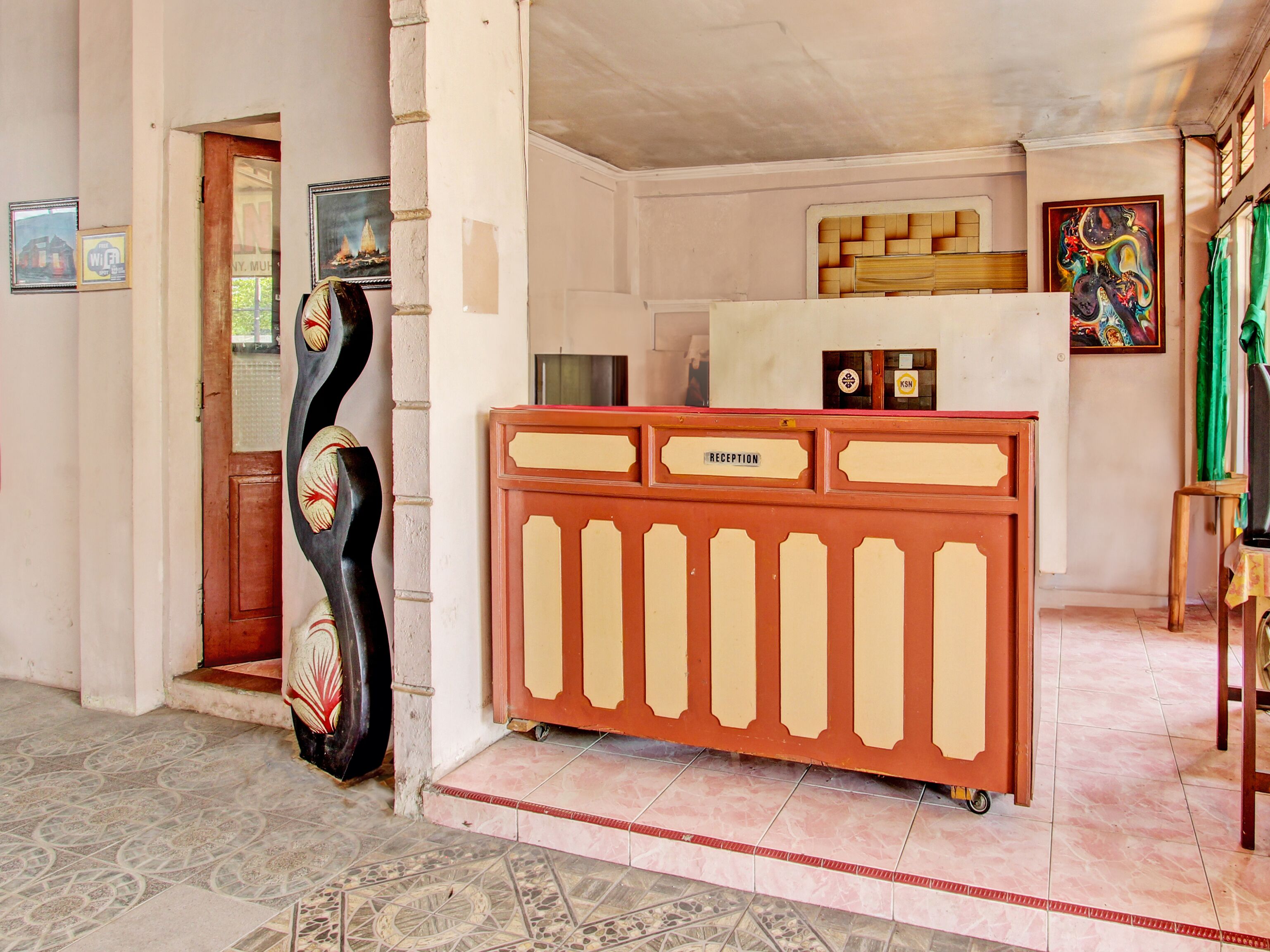 A reception area with a reception desk labeled "RECEPTION," a tiled floor, and a wall with a framed picture and a sign.