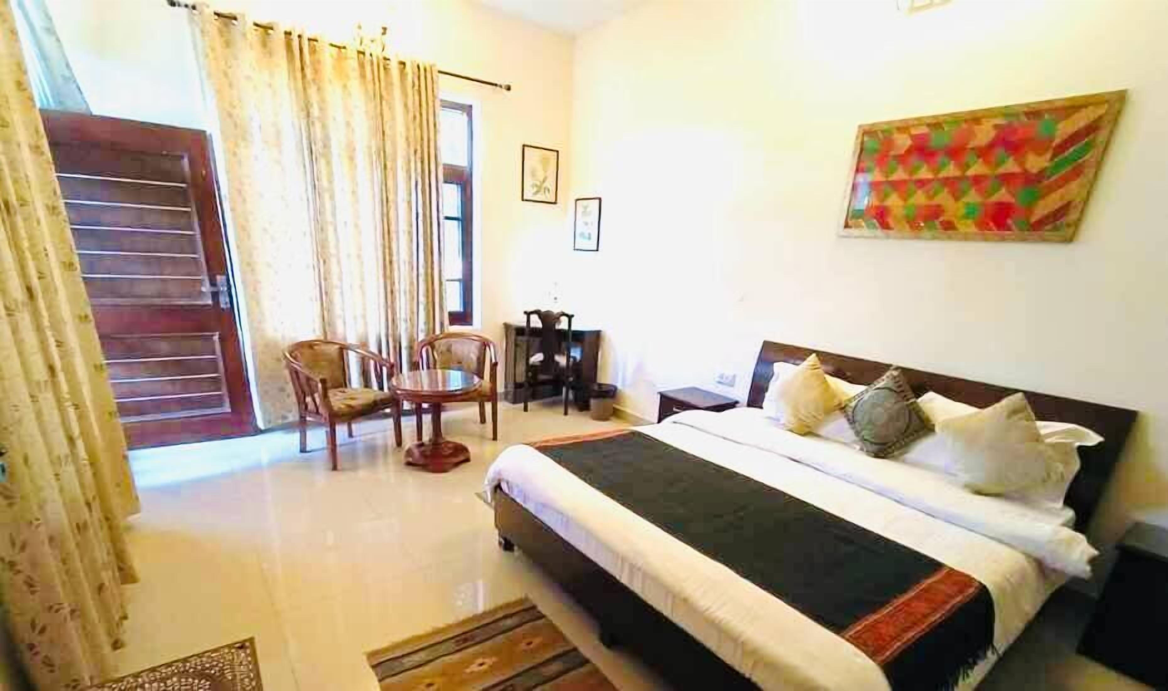 A bedroom with a bed, a desk, and two chairs.