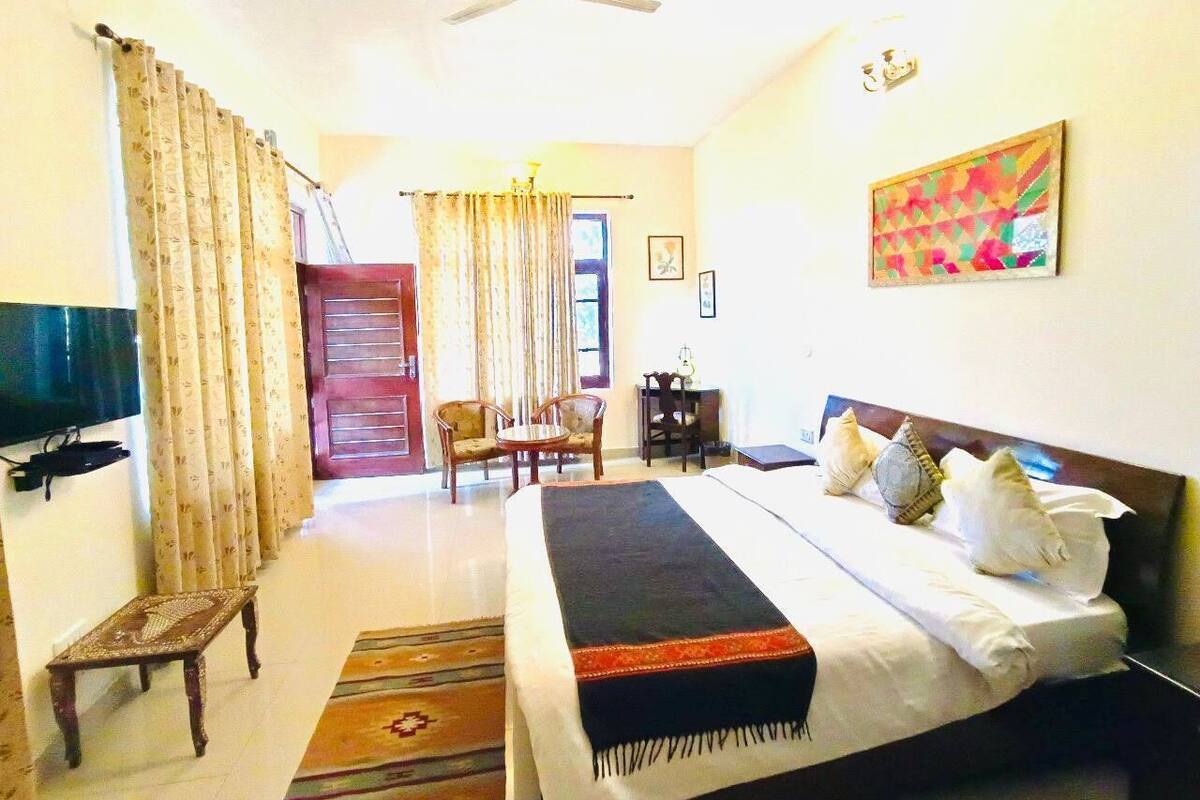 A hotel room with a bed, a desk, a chair, a television, and a ceiling fan.