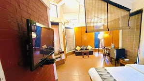 Een hotelkamer met een televisie aan de muur, een bed, een bank en een bureau met een stoel.