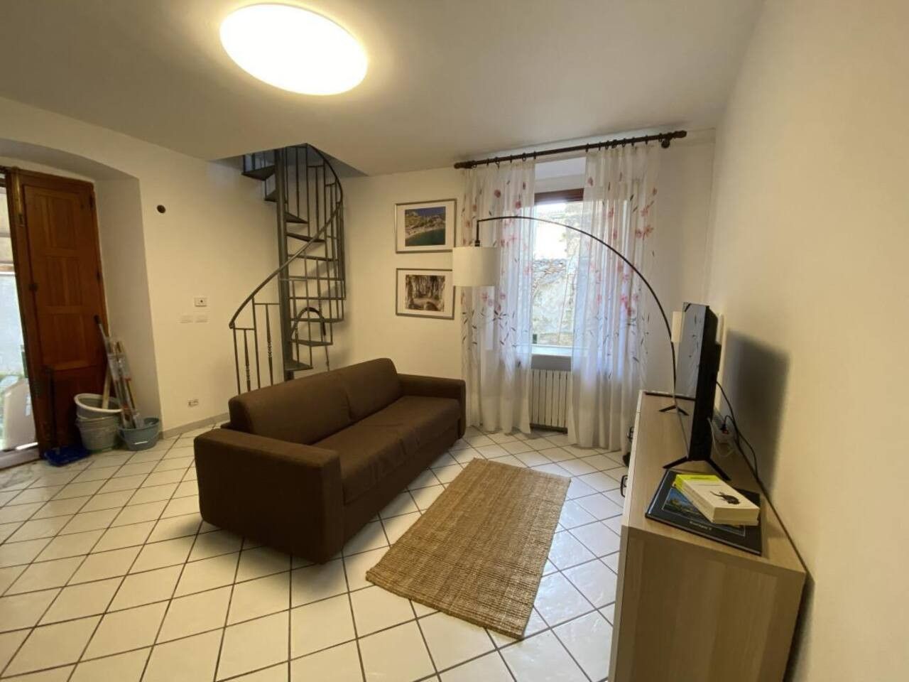 A living room with a sofa, a rug, a TV stand, and a staircase.