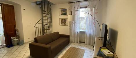 A living room with a sofa, a rug, a TV stand, and a staircase.