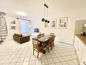 A dining area with a table and chairs, a sofa, a television, and framed pictures on the wall. - Casa Edoardo Two Bedroom Pizzo Calabro (Pizzo)