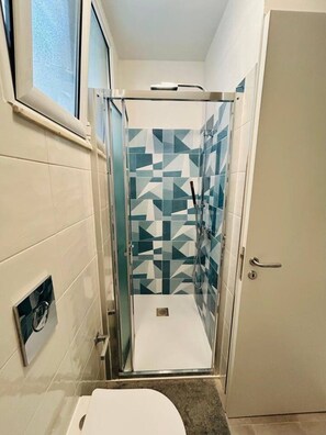 A bathroom with a shower stall, a toilet, and a door.