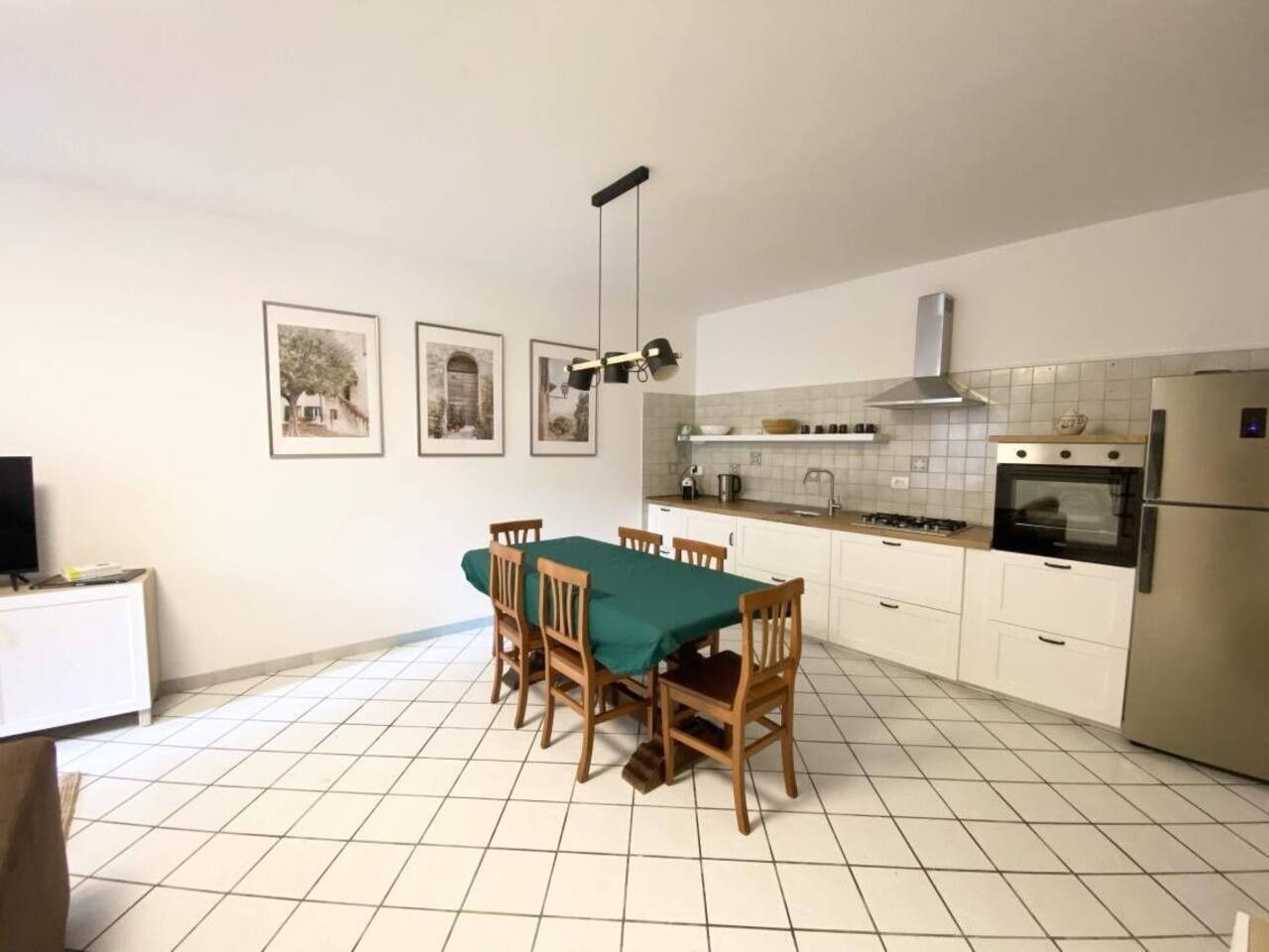 Una cucina con tavolo da pranzo, sedie, piano cottura, forno e frigorifero.