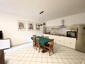 A kitchen with a dining table, chairs, a stove, oven, and a refrigerator. - Casa Edoardo Two Bedroom Pizzo Calabro (Pizzo)