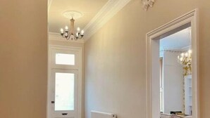 A hallway with a wooden herringbone floor, a white radiator, and a chandelier. - Luxury Glasgow West End Apt.

 (Glasgow)