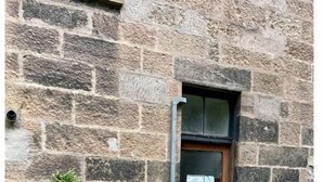 A stone building with a wooden door, potted plants, and a small garden area. - Luxury Glasgow West End Apt.

 (Glasgow)