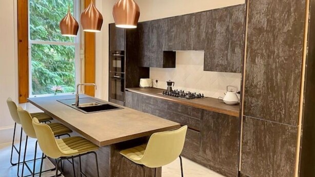A modern kitchen with a central island, pendant lights, and a view of greenery outside. - Luxury Glasgow West End Apt.

 (Glasgow)