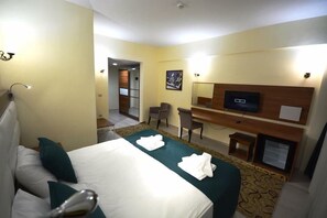 Una habitación de hotel con cama, escritorio, silla, televisión y baño.