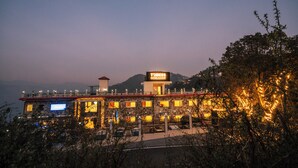 A hotel with a prominent sign, stone facade, and a view of mountains in the background. - Trideus Chandseena Valley Resort (Dehradun)