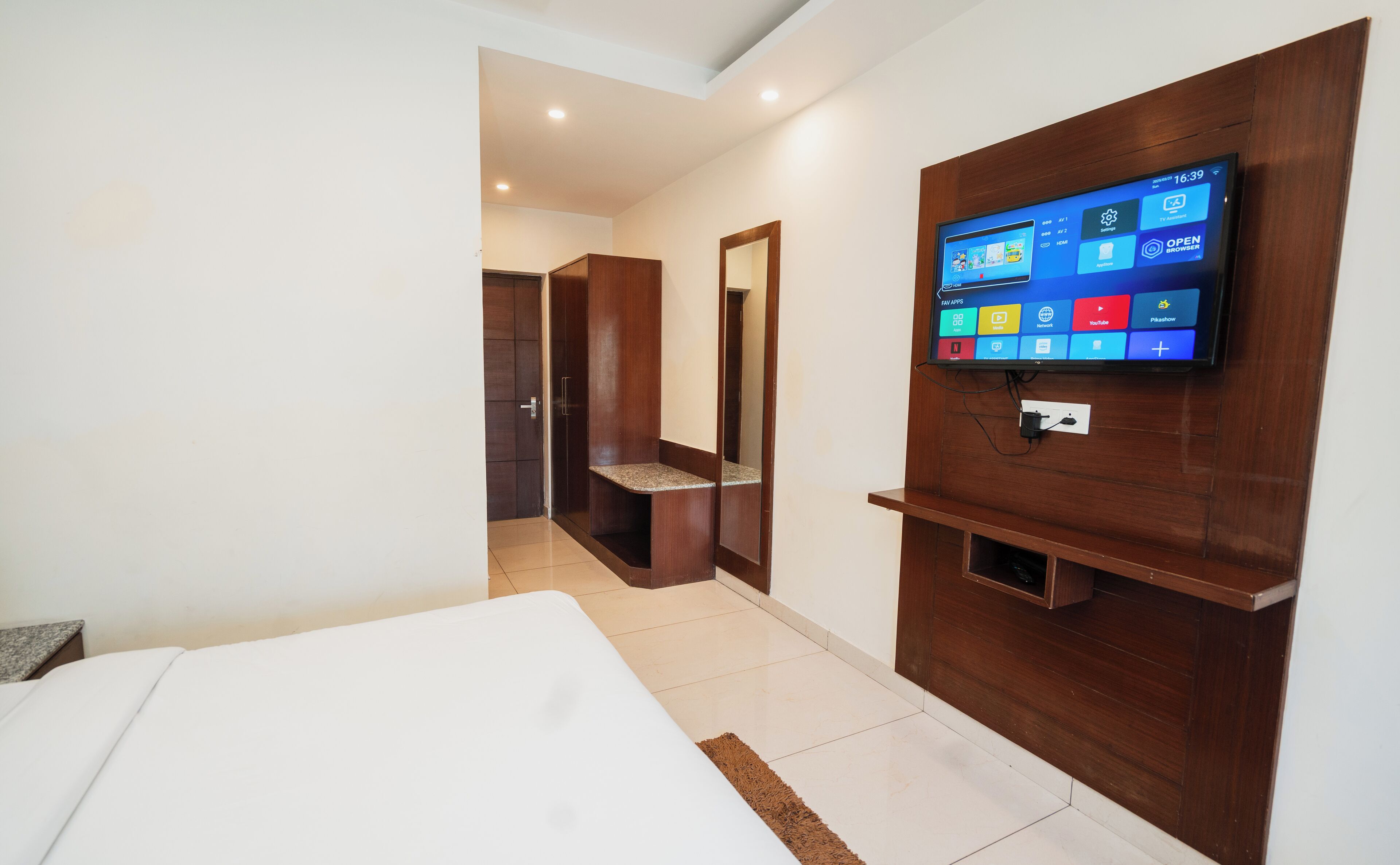 Ein Hotelzimmer mit einem Bett, einem an der Wand befestigten Fernseher und einem Holzschrank.