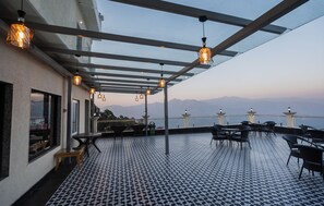 Terraza al aire libre con suelo a cuadros, mesas, sillas y faroles colgantes.