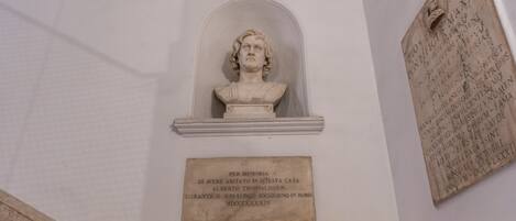 A marble bust in a niche with a plaque below it.