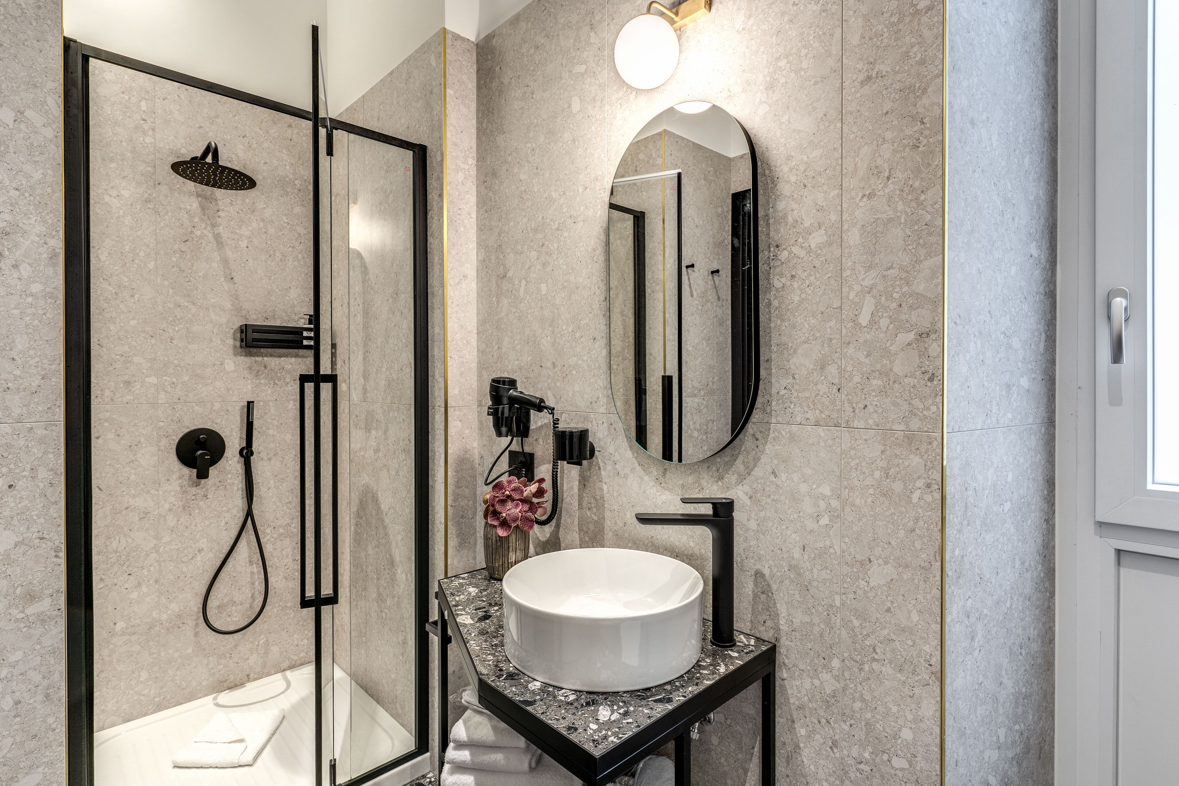 A modern bathroom with a glass-enclosed shower, a round sink, and a large mirror.