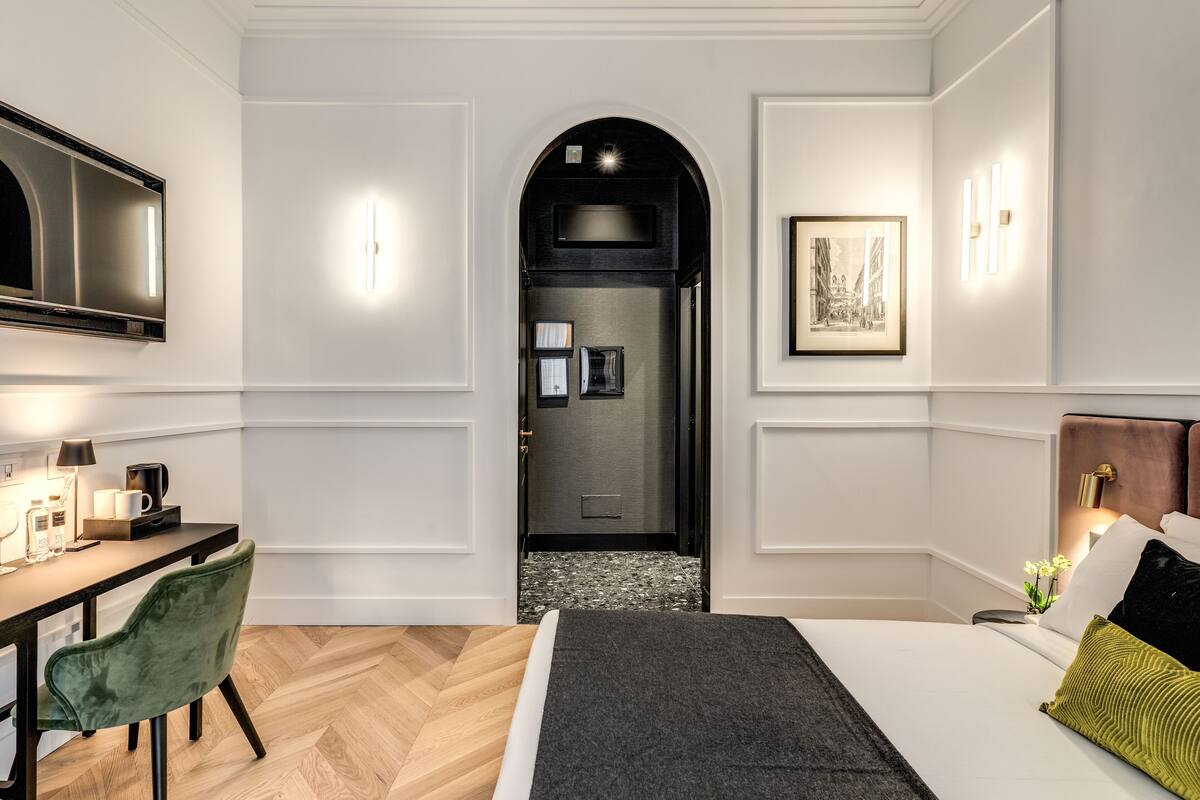 A modern hotel room with a bed, desk, chair, and a television.