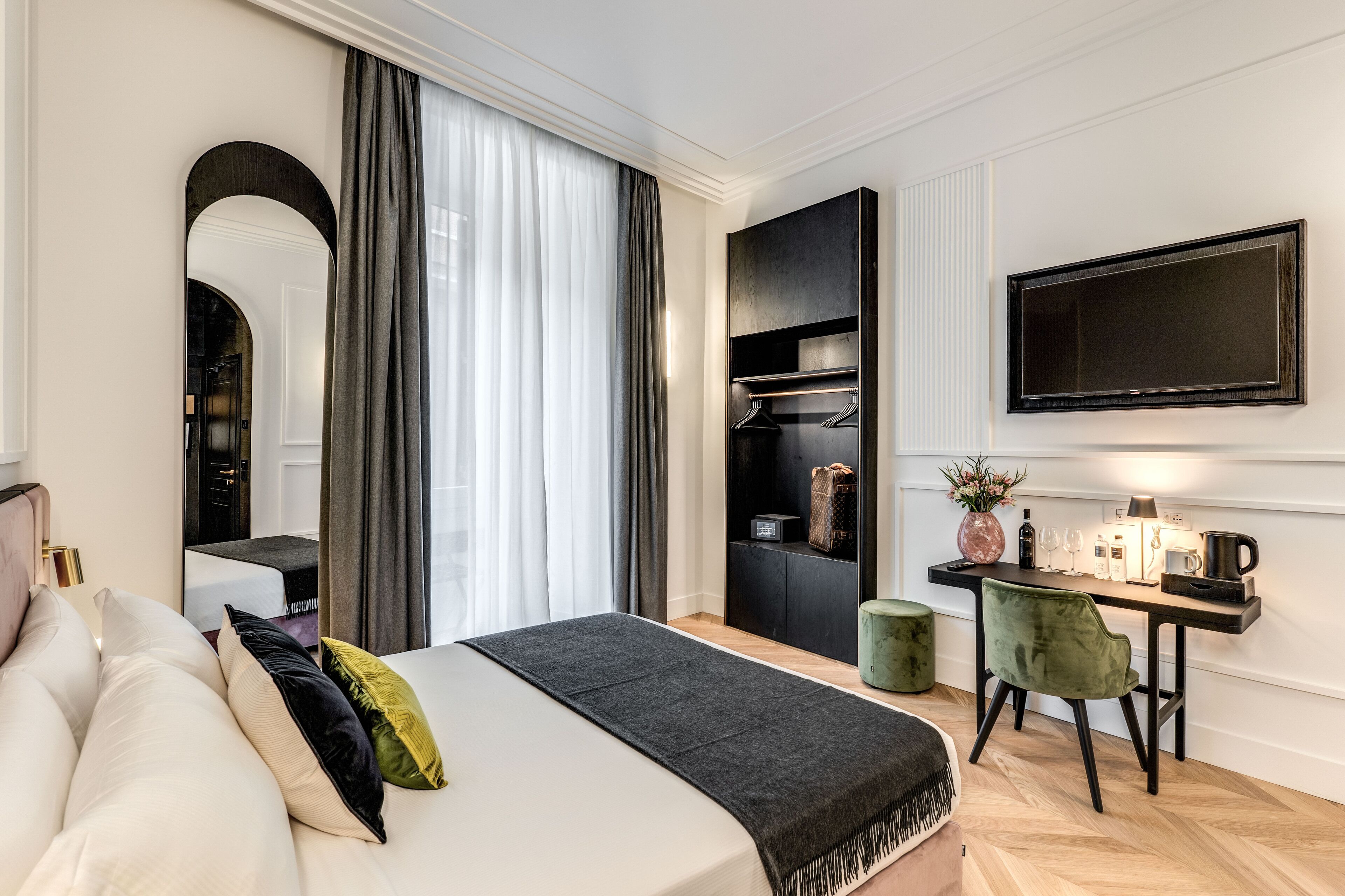 Habitació d'hotel moderna amb llit, escriptori amb cadira, televisió i armari.
