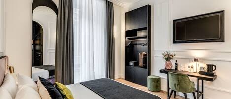 A modern hotel room with a bed, a desk with a chair, a TV, and a wardrobe.