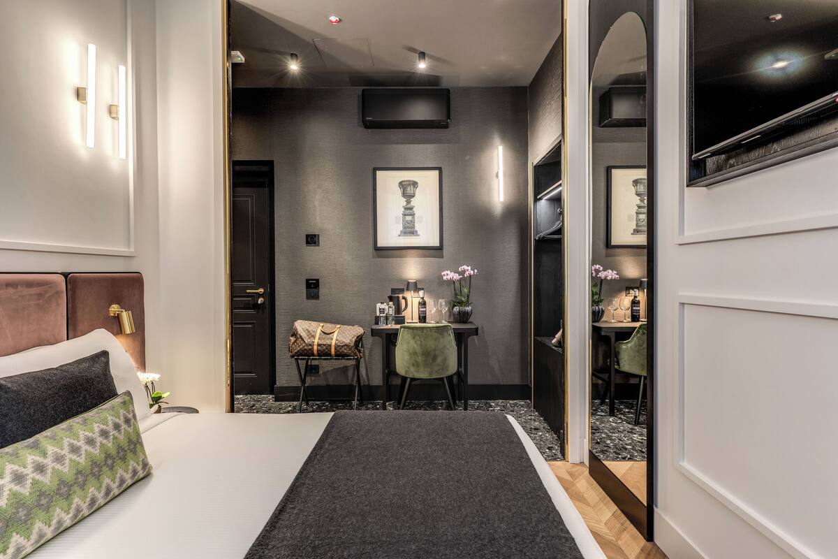A modern hotel room with a bed, a desk, and a dining area.