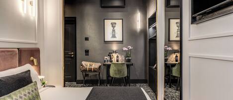 A modern hotel room with a bed, a desk, and a dining area.