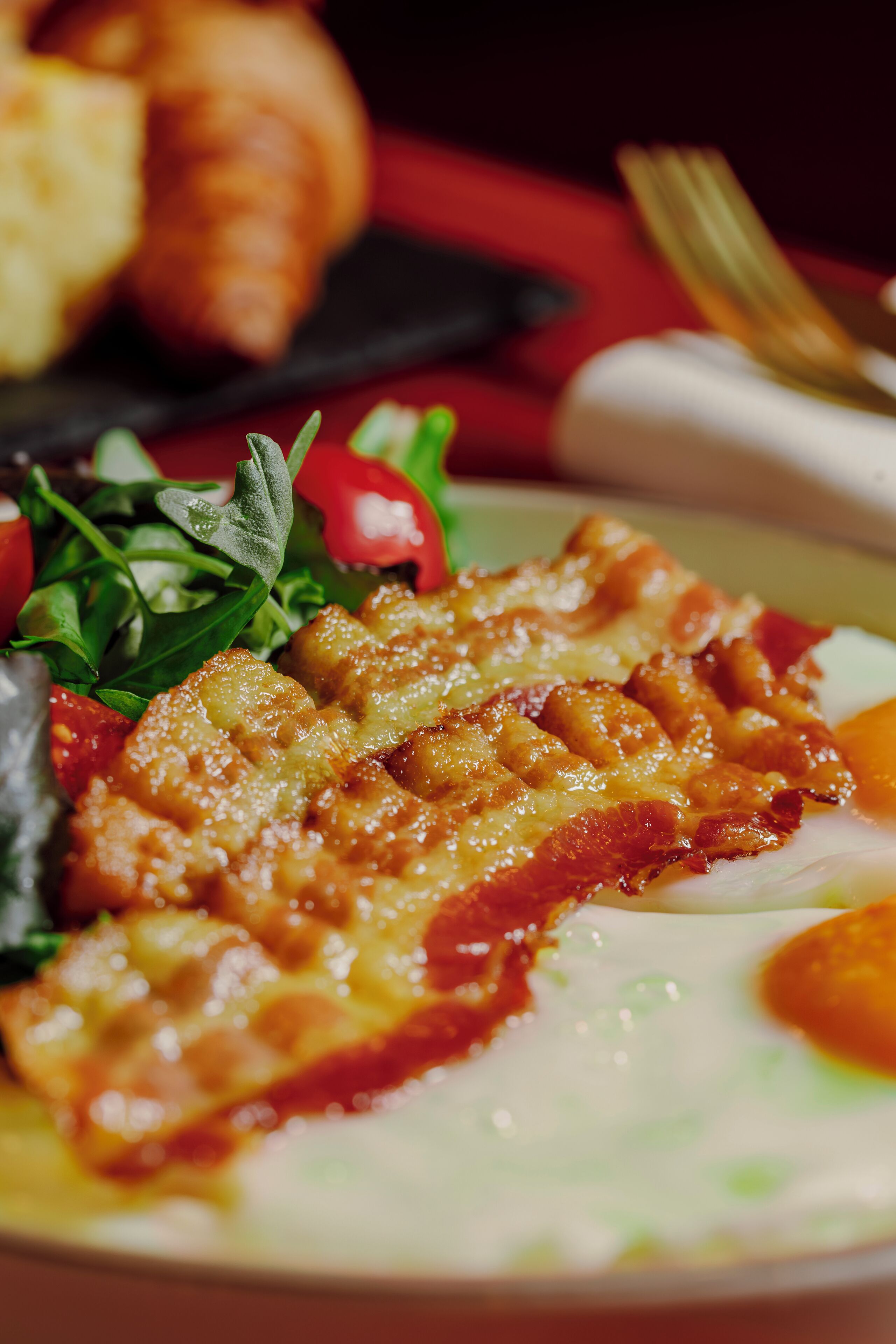 A close-up of a meal with a golden-brown crust, green vegetables, and a red sauce.