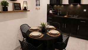 Una cocina moderna con gabinetes negros, una mesa redonda de comedor con sillas negras y un letrero de bienvenida en la pared.
